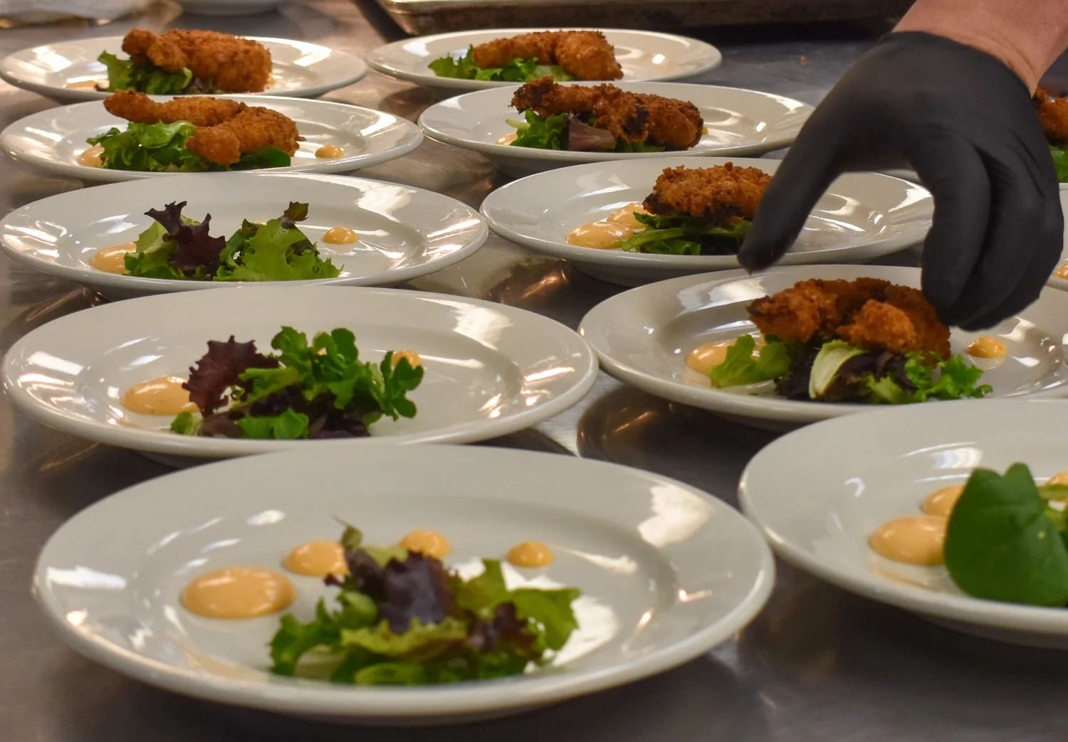 An SPBH kitchen team member plating dishes for service