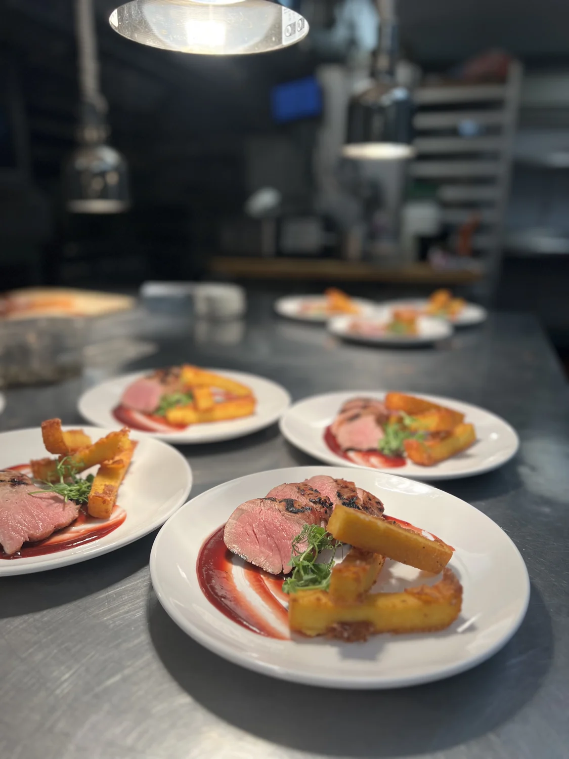 Sliced meat entrées with vegetables arranged on plates in the SPBH kitchen