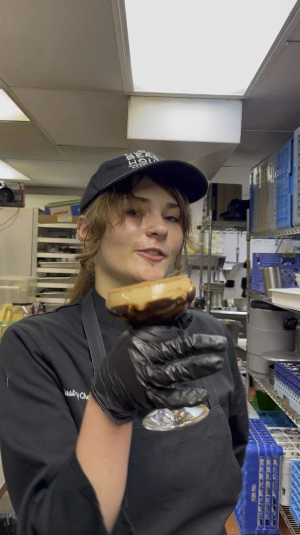 Emma, Sandy Point’s pastry chef, holding a finished dessert in the kitchen