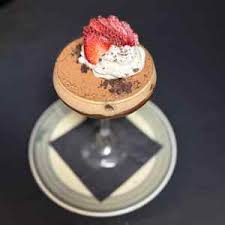Tiramisu in a stemmed glass topped with cream and strawberry